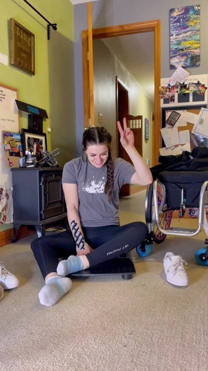 Jesi seated on a scale at home beside her wheelchair