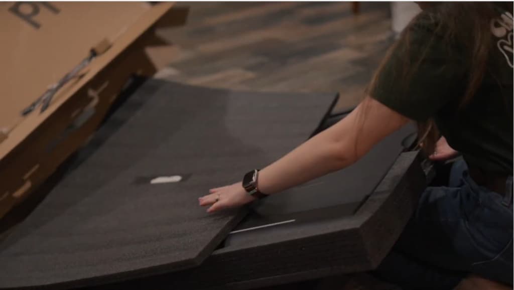 Hands opening Fold flat on the floor beside its packaging.